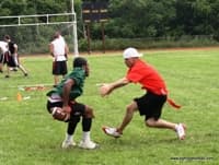 Defender lunging to pull the flag of a ball carrier tucking the football