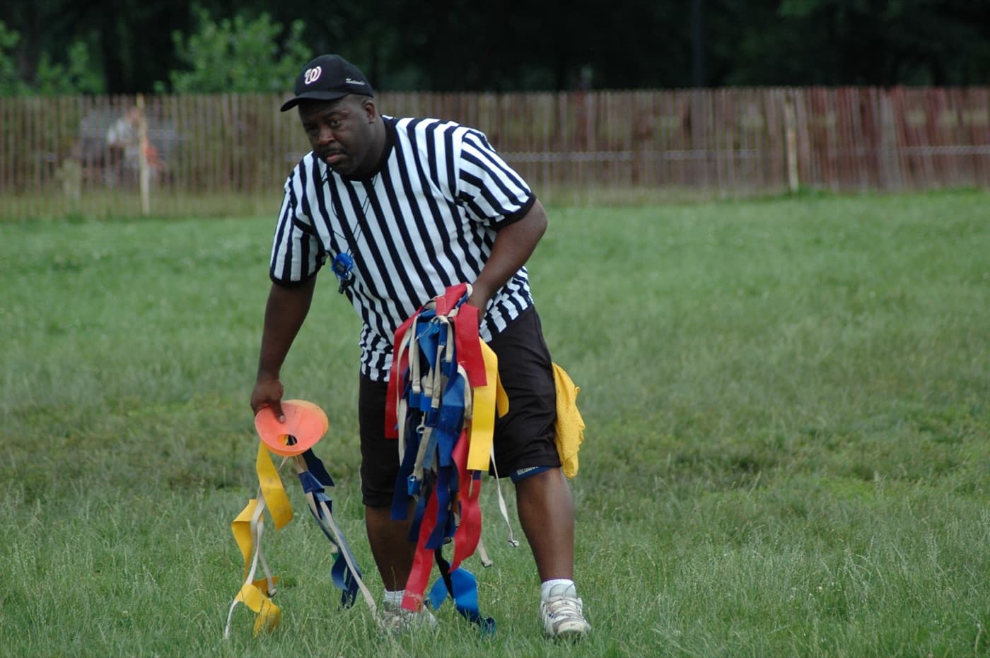 Referee gathering flag belts and a cone off the field between games